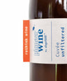 Eine Nahaufnahme der Naturweinflasche 'Unfiltered' von Pioneerwine in einer Mehrwegflasche mit einem wasserlöslichen Etikett. Das außergewöhnliche Design der Flasche und das umweltfreundliche Etikett spiegeln den nachhaltigen Ansatz der Marke wider und machen die Flasche besonders leicht wiederverwendbar.